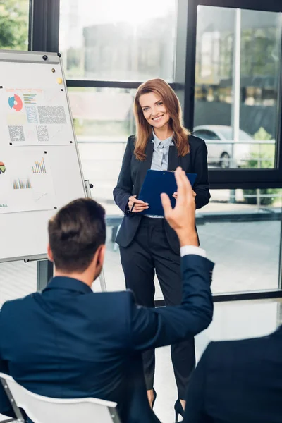 Lächelnde Wirtschaftsdozentin mit erhobener Hand beim Seminar im Konferenzsaal — Stockfoto