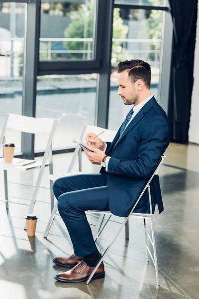 Seitenansicht des Geschäftsmannes mit Notizbuch im Konferenzsaal — Stockfoto