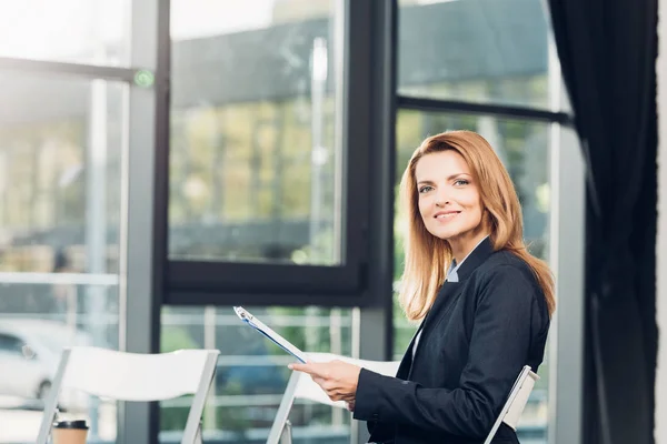 Side view of businesswoman with notepad waiting for lecture in conference hall — Stock Photo