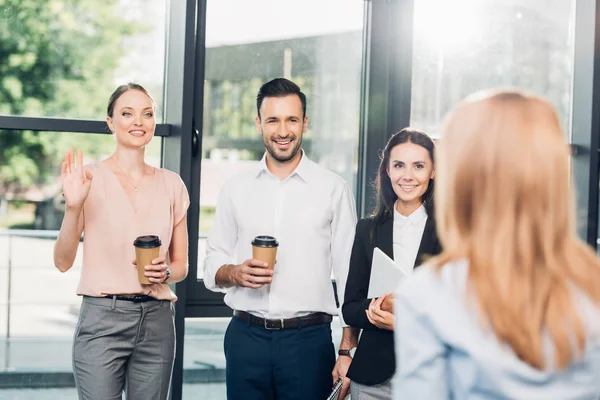 Sorrindo colegas olhando para empresária durante coffee break no escritório — Fotografia de Stock