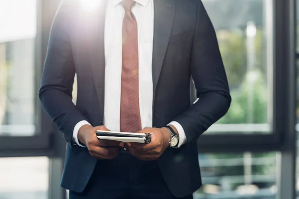 Cropped shot of african american businessman with notebook in conference hall — Stock Photo