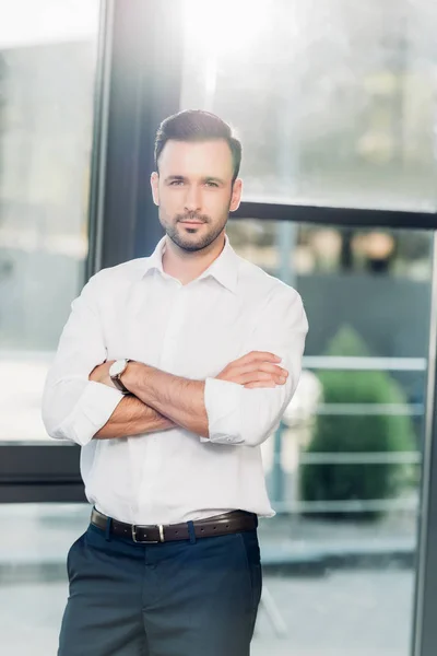 Retrato de hombre de negocios con los brazos cruzados de pie en la sala de conferencias - foto de stock