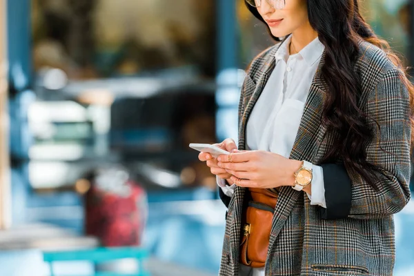 Cropped image of woman using smartphone on street near cafe — Stock Photo