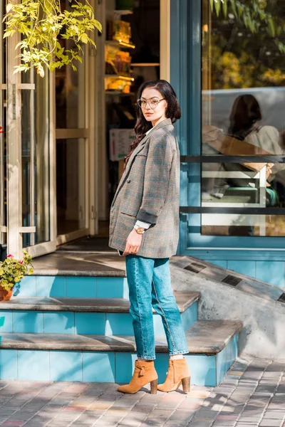 Schöne brünette Frau steht in der Nähe von Treppen zum Café auf der Straße und schaut weg — Stockfoto