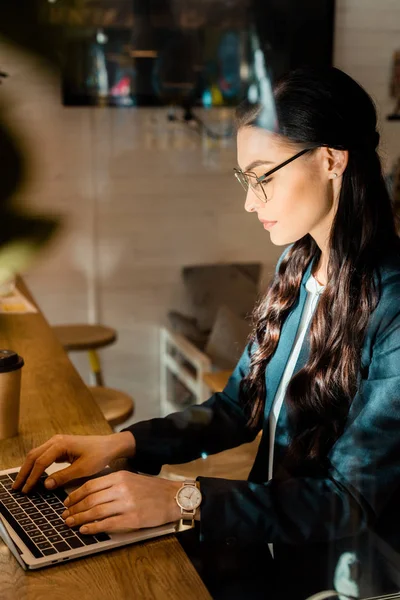 Bella bruna telelavoro in occhiali utilizzando il computer portatile al ristorante — Foto stock