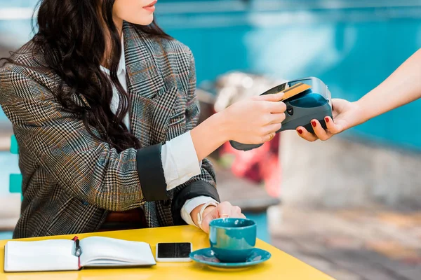 Cropped view of woman paying with credit card on payment terminal in cafe — Stock Photo