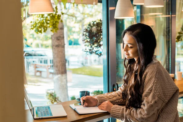 Beautiful freelancer working with planner and laptop in coffee shop — Stock Photo