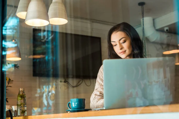 Freelancer feminino bonito com xícara de café trabalhando no laptop no café — Fotografia de Stock