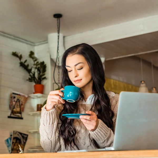 Casual businesswoman in autumn sweater drinking coffee in cafe with laptop — Stock Photo
