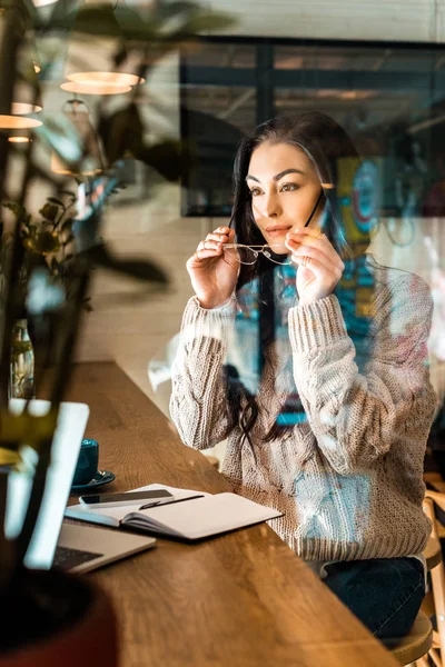 Beautiful female freelancer in eyeglasses working in cafe — Stock Photo