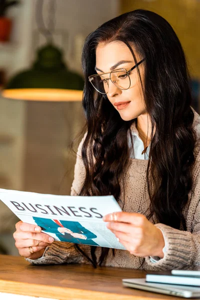 Attractive brunette woman reading business newspaper at restaurant — Stock Photo