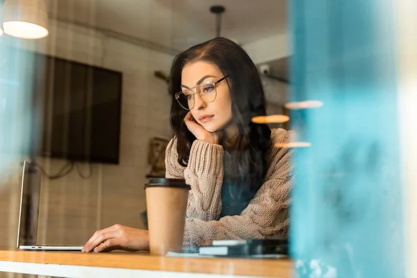 Attractive bored freelancer in cafe with laptop and coffee to go — Stock Photo