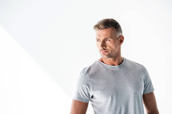 Schöner erwachsener Mann in leerem grauen T-Shirt, der isoliert auf weißem Grund wegschaut — Stockfoto