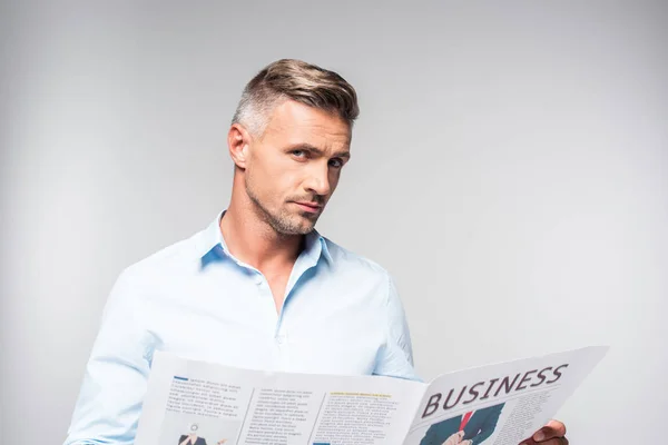 Gutaussehender erwachsener Geschäftsmann mit Wirtschaftszeitung, der isoliert auf weiß in die Kamera blickt — Stockfoto