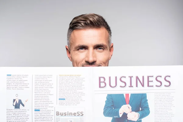 Close-up tiro de belo empresário adulto cobrindo rosto com jornal de negócios isolado em branco — Fotografia de Stock