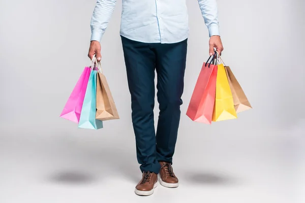Schnappschuss eines Mannes, der bunte Einkaufstüten auf weißem Grund trägt — Stockfoto