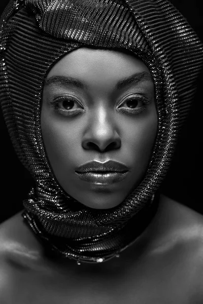 Foto en blanco y negro de la elegante mujer afroamericana mirando a la cámara aislada en negro - foto de stock