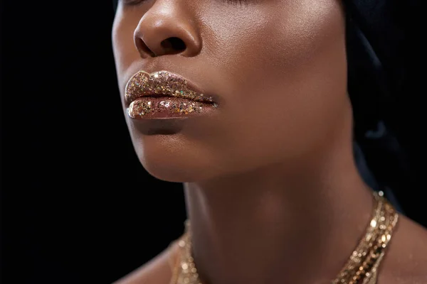 Обрезанный снимок африканской американки с блестящим блеском для губ, изолированный на черном — стоковое фото