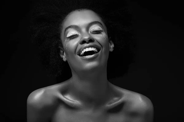 Black and white photo of cheerful african american woman isolated on black — Stock Photo