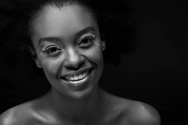 Black and white photo of cheerful african american woman isolated on black — Stock Photo