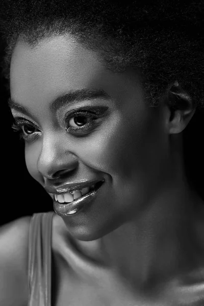 Чорно-біле фото красивої усміхненої афроамериканської жінки ізольовано на чорному — стокове фото