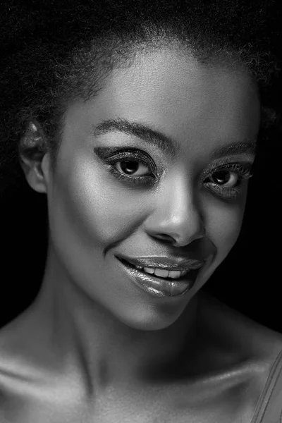 Черно-белое фото красивой африканской женщины, смотрящей в камеру, изолированную на черном — стоковое фото