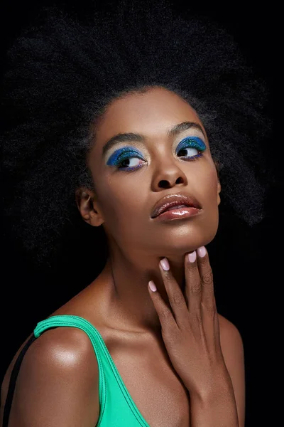 Retrato de modelo afroamericano pensativo con ojos azules brillantes sombras aisladas en negro - foto de stock