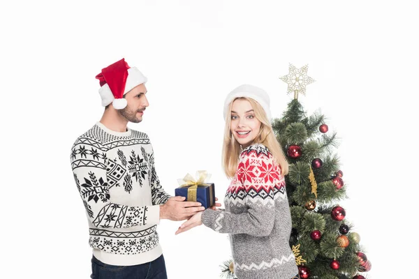 Seitenansicht des Mannes präsentiert verpacktes Geschenk an lächelnde Freundin am Weihnachtsbaum isoliert auf weiß — Stockfoto