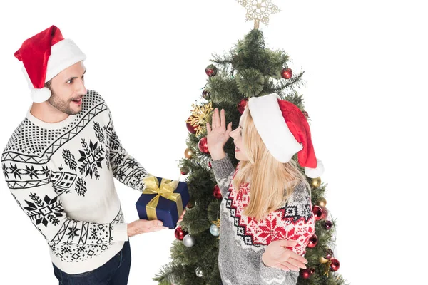 High angle view of man presenting wrapped gift to surpsrised girlfriend at christmas tree isolated on white — Stock Photo