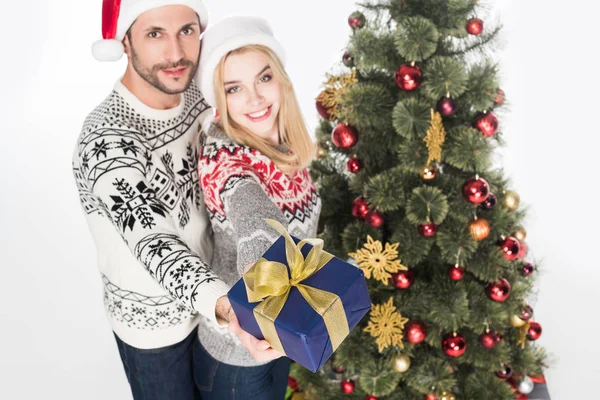 Vue grand angle du couple montrant cadeau enveloppé près de l'arbre de Noël isolé sur blanc — Photo de stock