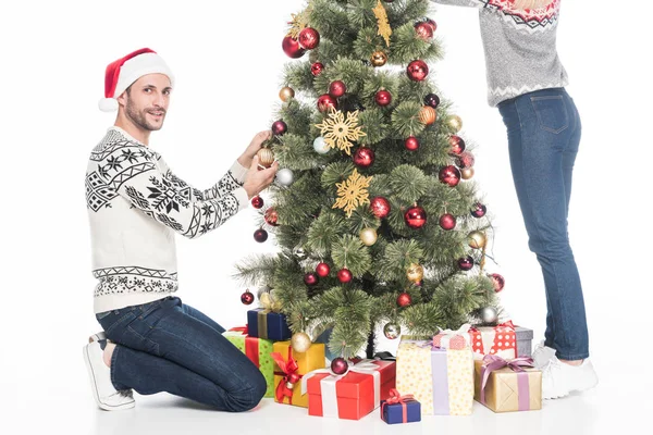 Vista parcial de pareja en suéteres decorando árbol de Navidad juntos aislados en blanco - foto de stock