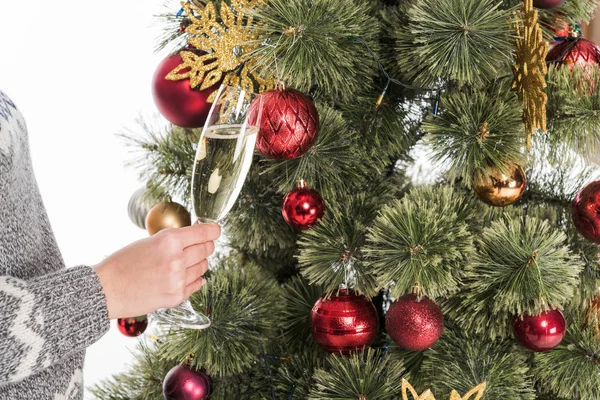 Tiro recortado de mujer en suéter con copa de champán cerca del árbol de Navidad aislado en blanco - foto de stock