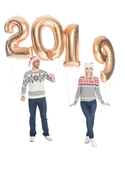 Stylish couple in sweaters and santa claus hats with 2019 balloons isolated on white, 2019 new year concept — Stock Photo