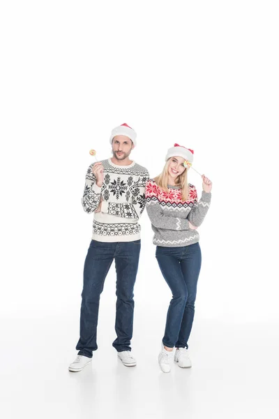 Kaukasisches Paar in Weihnachtsmannhüten mit Lutschern auf weißem Grund — Stockfoto