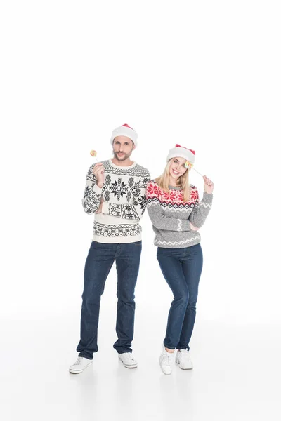 Pareja caucásica en sombreros de santa claus con piruletas aisladas en blanco — Stock Photo