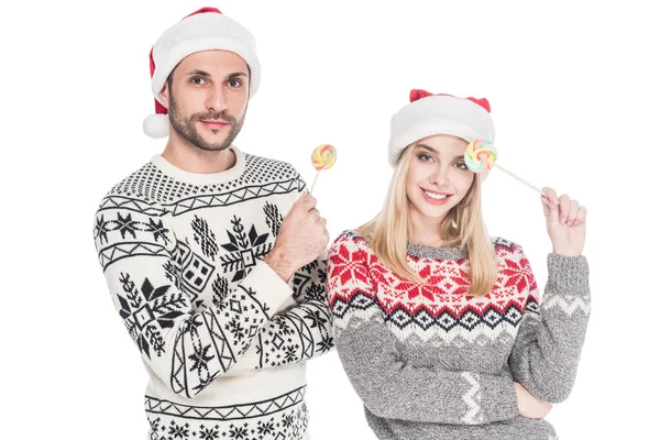 Portrait of young caucasian couple in santa claus hats with lollipops isolated on white — Stock Photo