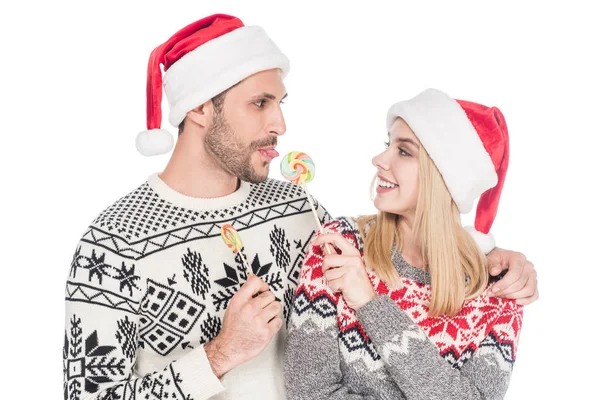 Ritratto di giovane coppia caucasica in cappelli di Babbo Natale con lecca-lecca isolati su bianco — Foto stock