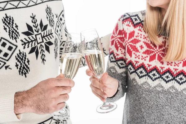 Recortado disparo de pareja en suéteres tintineo vasos de champán aislado en blanco - foto de stock