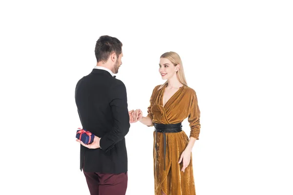 Стильний чоловік дивує усміхнену дівчину з подарунком ізольовано на білому — стокове фото