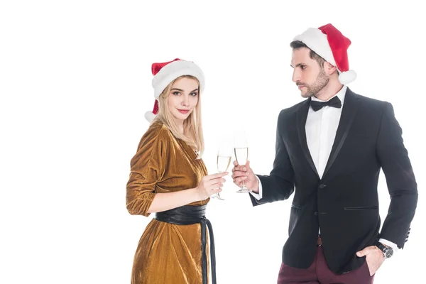 Couple élégant dans santa claus chapeaux cliquetis verres de champagne isolé sur blanc — Photo de stock