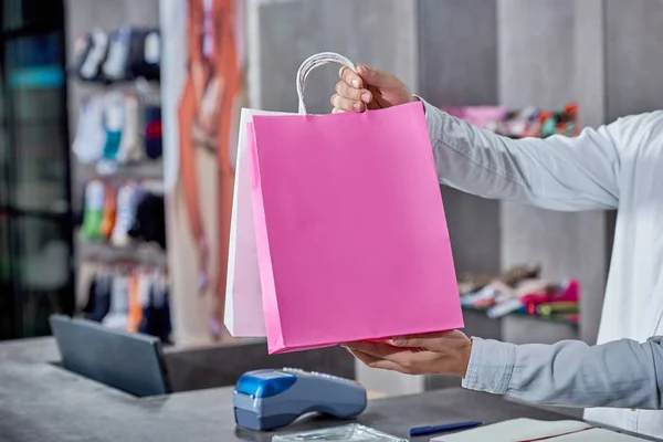 Partial view of young salesman holding paper bags in shop — Stock Photo