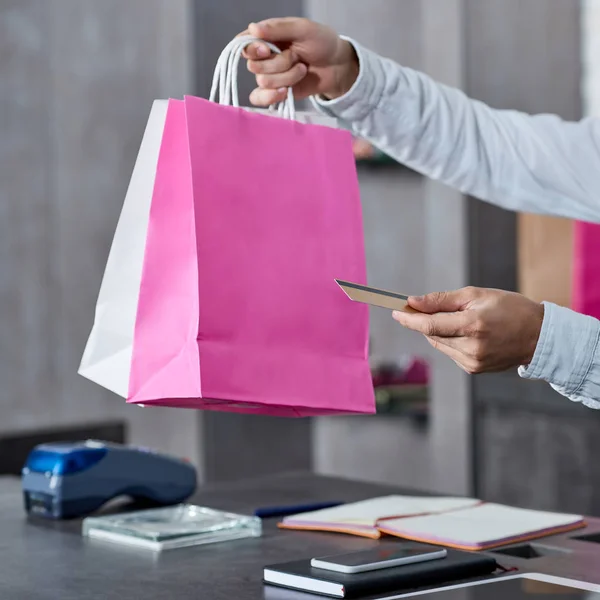 Обрізаний знімок продавця, який тримає паперові пакети та кредитну картку в магазині — стокове фото
