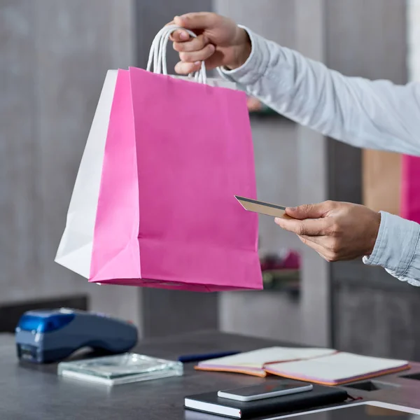 Cropped shot of salesman holding paper bags and credit card in shop — Stock Photo