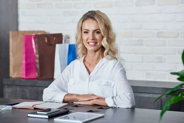 Attrayant jeune femme souriant à la caméra tout en travaillant en magasin — Photo de stock