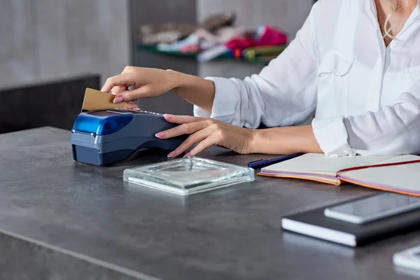 Plan recadré de jeune vendeuse détenant une carte de crédit et utilisant le terminal de paiement dans la boutique — Photo de stock
