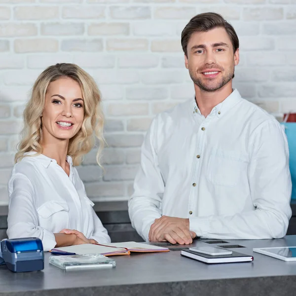 Glückliche junge Mitarbeiter lächeln während der gemeinsamen Arbeit im Geschäft in die Kamera — Stockfoto