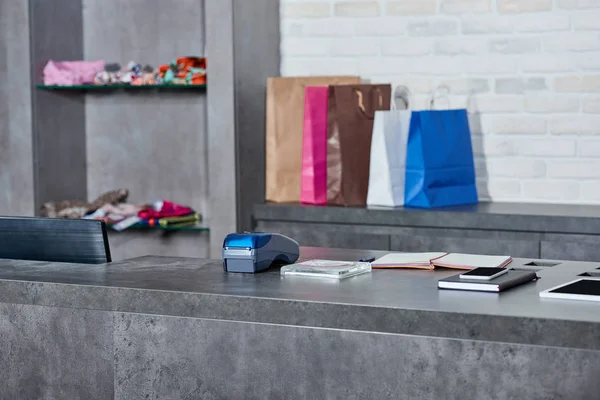 Digital devices, payment terminal and paper bags in shop — Stock Photo