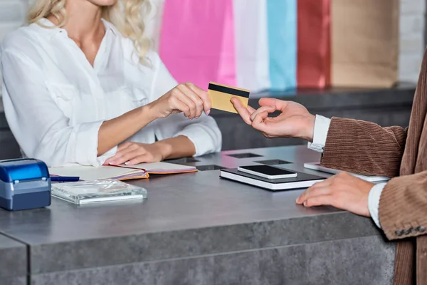 Tiro cortado de cliente dando cartão de crédito ao vendedor na loja — Fotografia de Stock