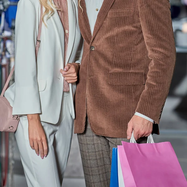 Recortado tiro de elegante pareja sosteniendo bolsas de compras en el centro comercial - foto de stock
