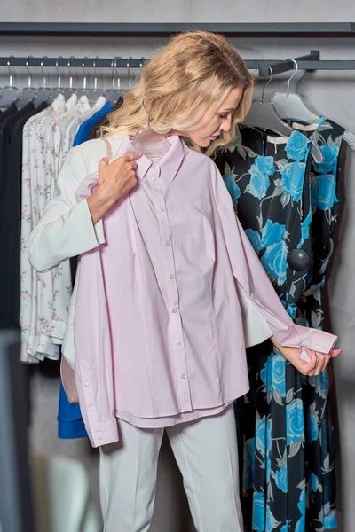 Attraktive Frau mit Kleiderbügel und modischem Hemd in Boutique — Stockfoto